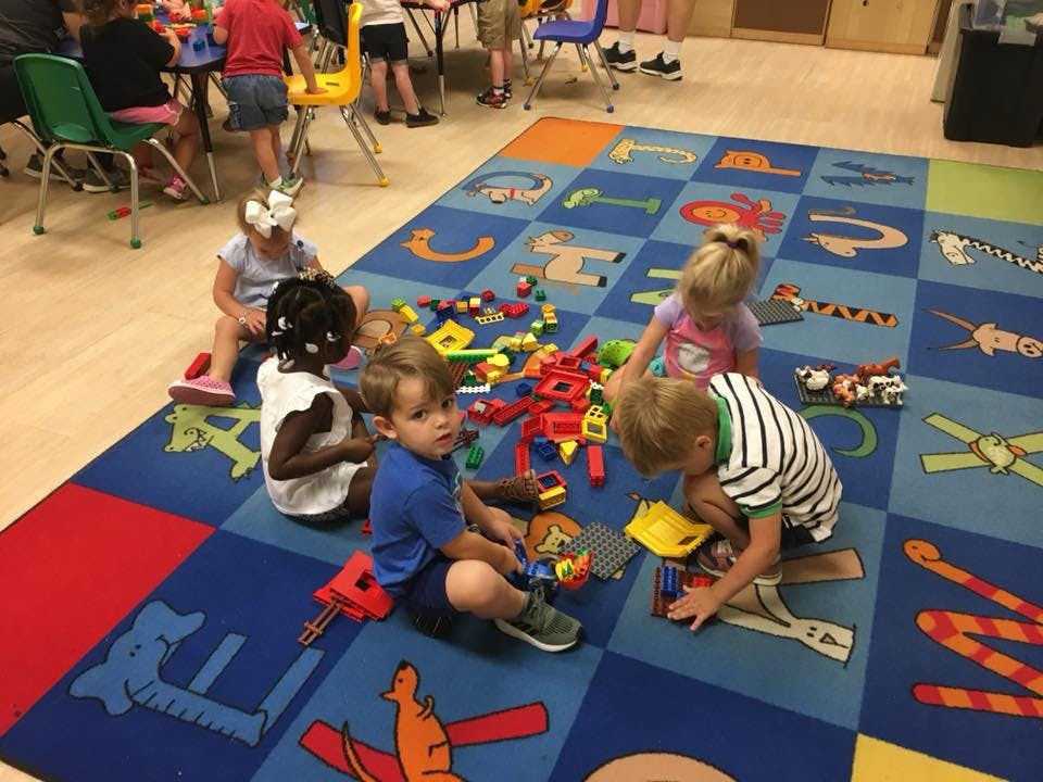 Children playing with toys on a colorful alphabet rug