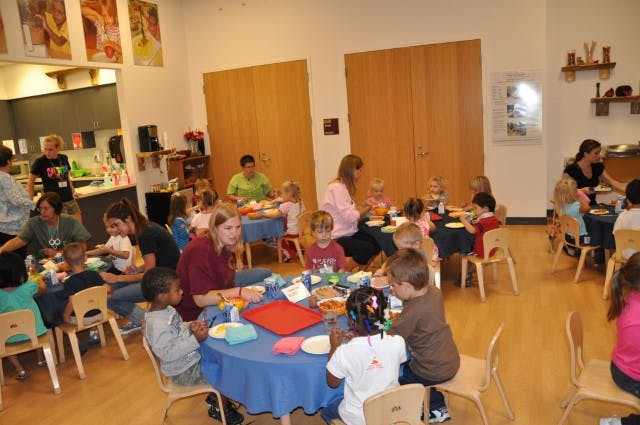 Adults and children sitting at tables in a room