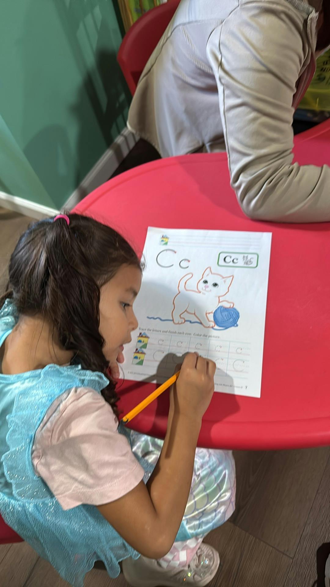 Child practicing writing the letter C on a worksheet
