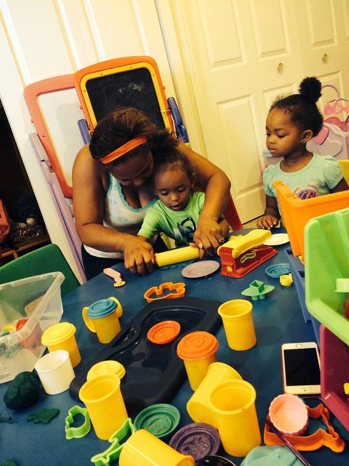 Person and child playing with modeling clay at a table