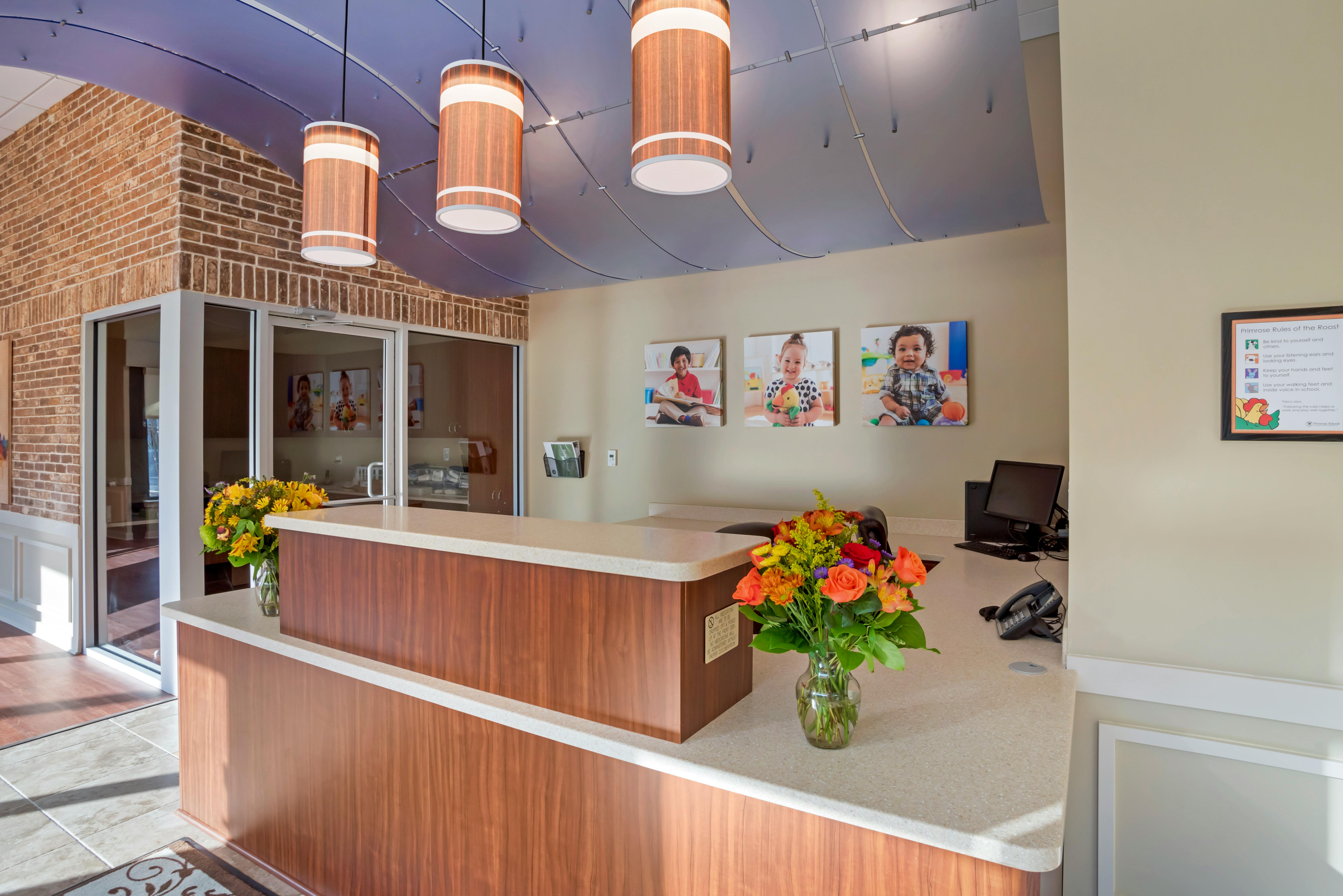 Reception desk with flower arrangements, computer, and three framed photos of children