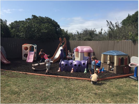 Children playing on a playground with slides and playhouses