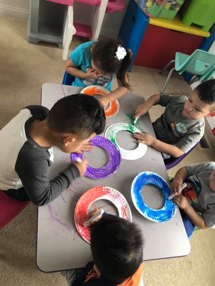 Children coloring paper plates at a table