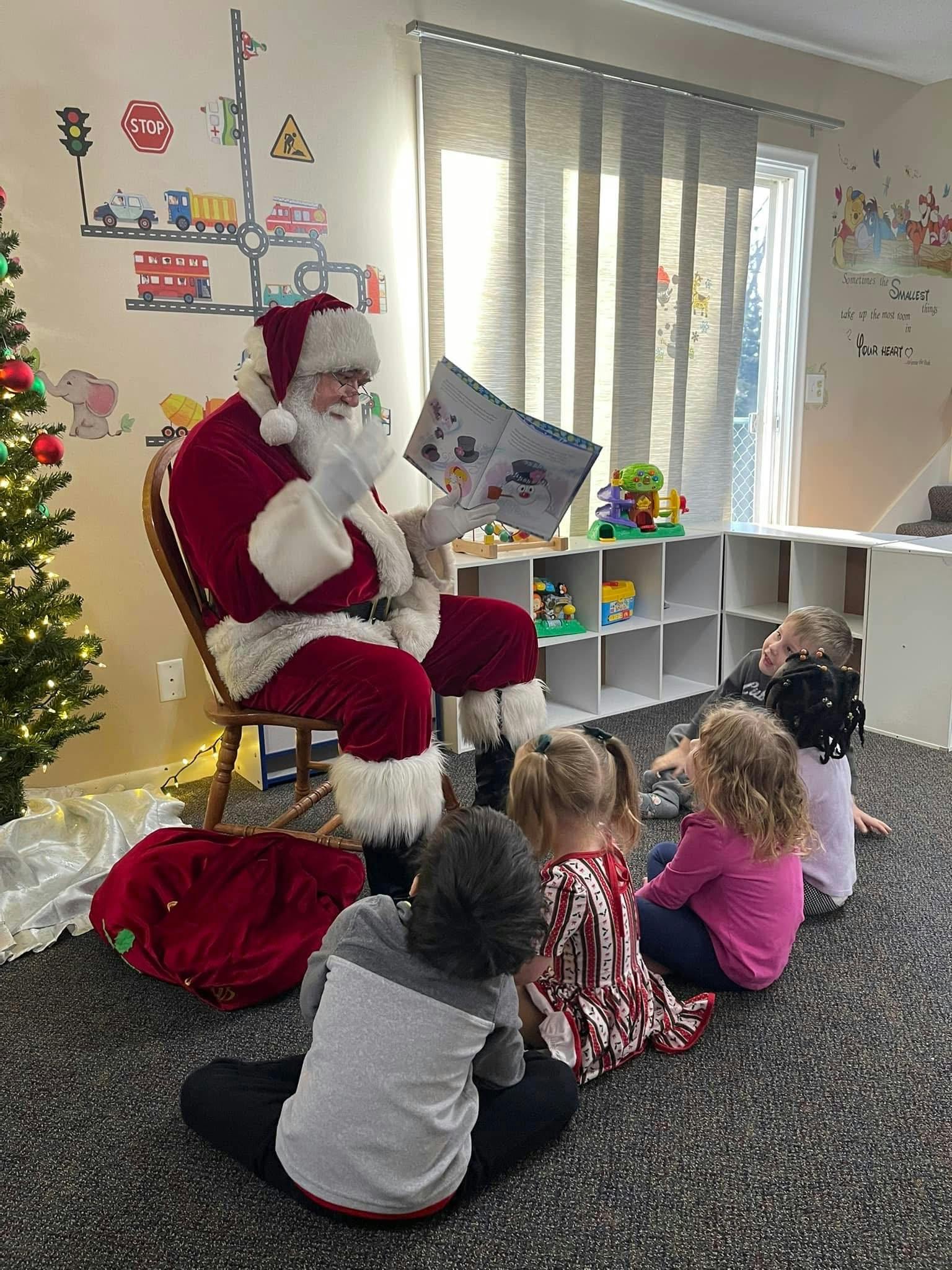 Person dressed as Santa Claus reading a book to a group of children