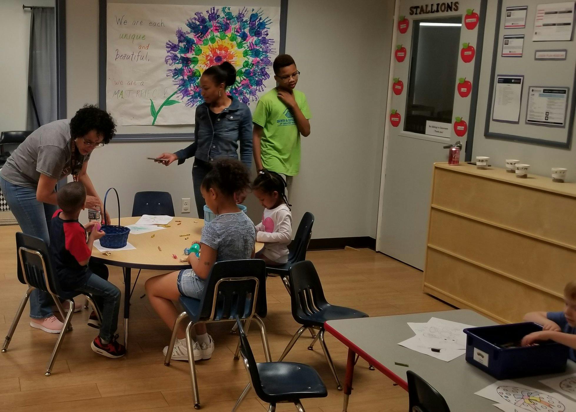 Adults and children gathered around a table in a classroom