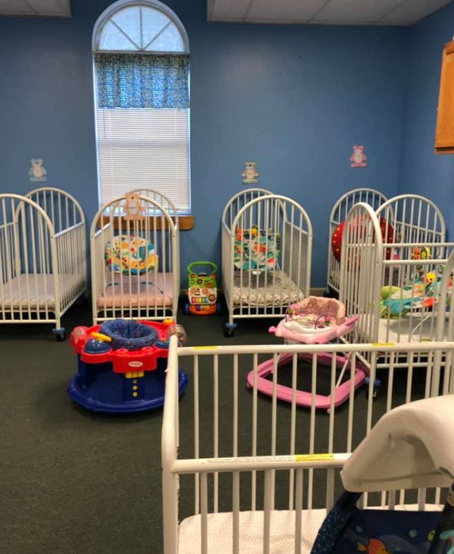 Multiple white cribs and baby play equipment in a room
