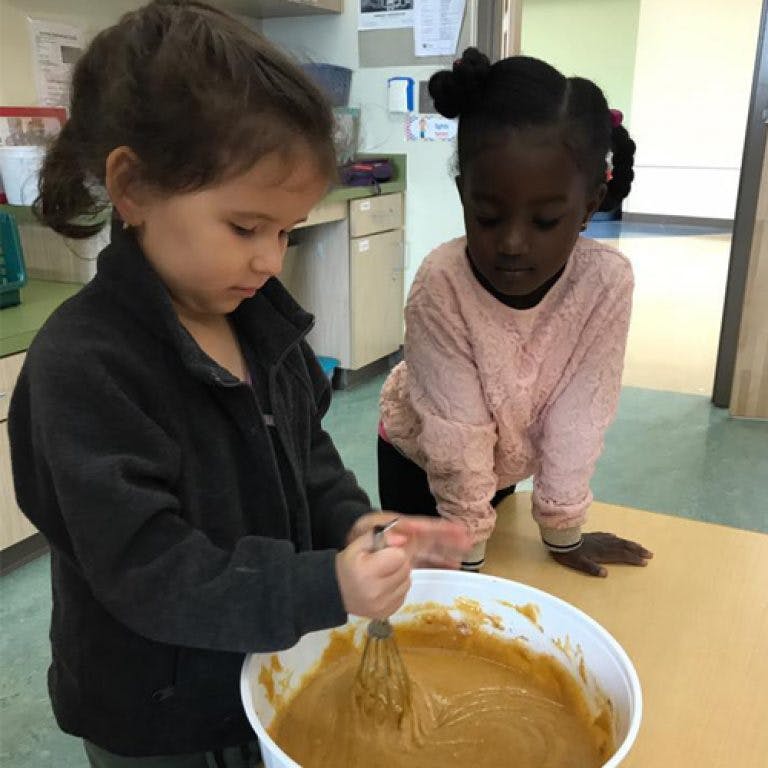 Two children mixing batter in a bowl