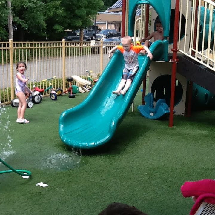 Child sliding down a playground slide with water splashing