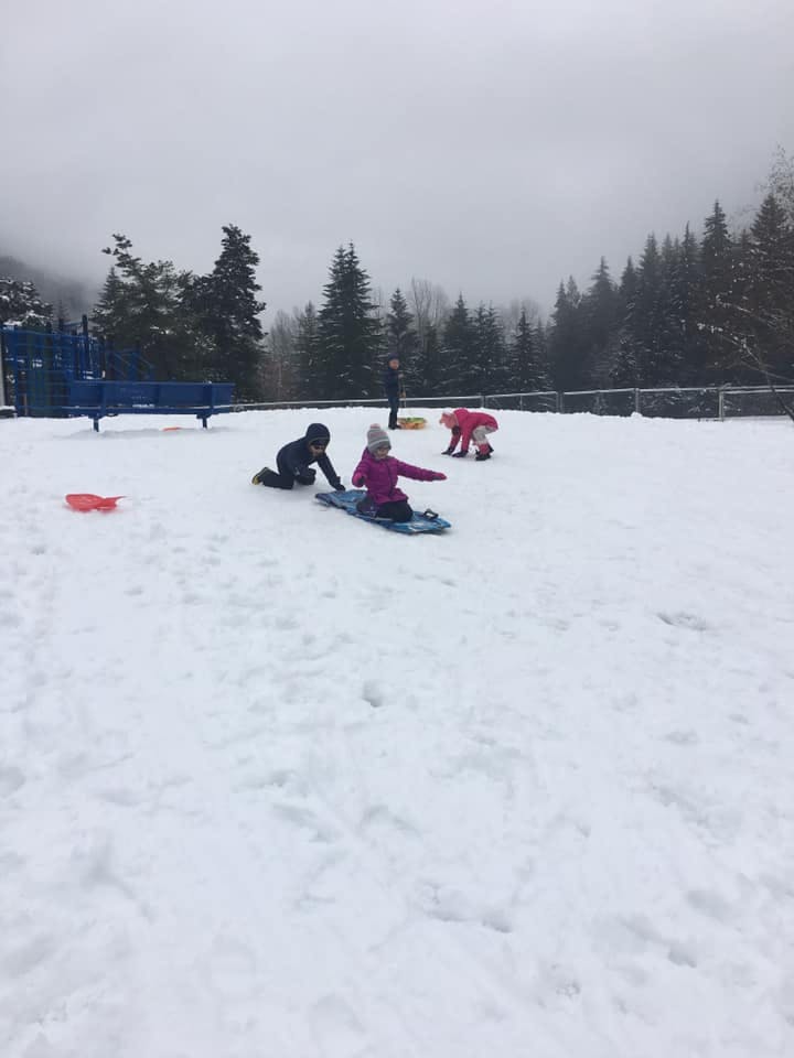 Children playing in the snow with sleds