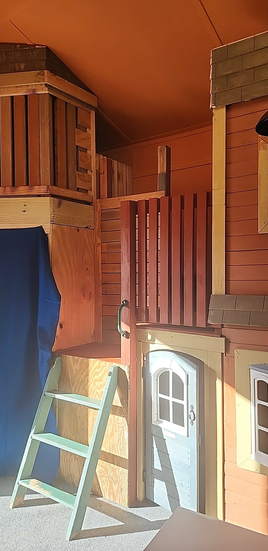 Indoor playhouse with a ladder, door, and upper level
