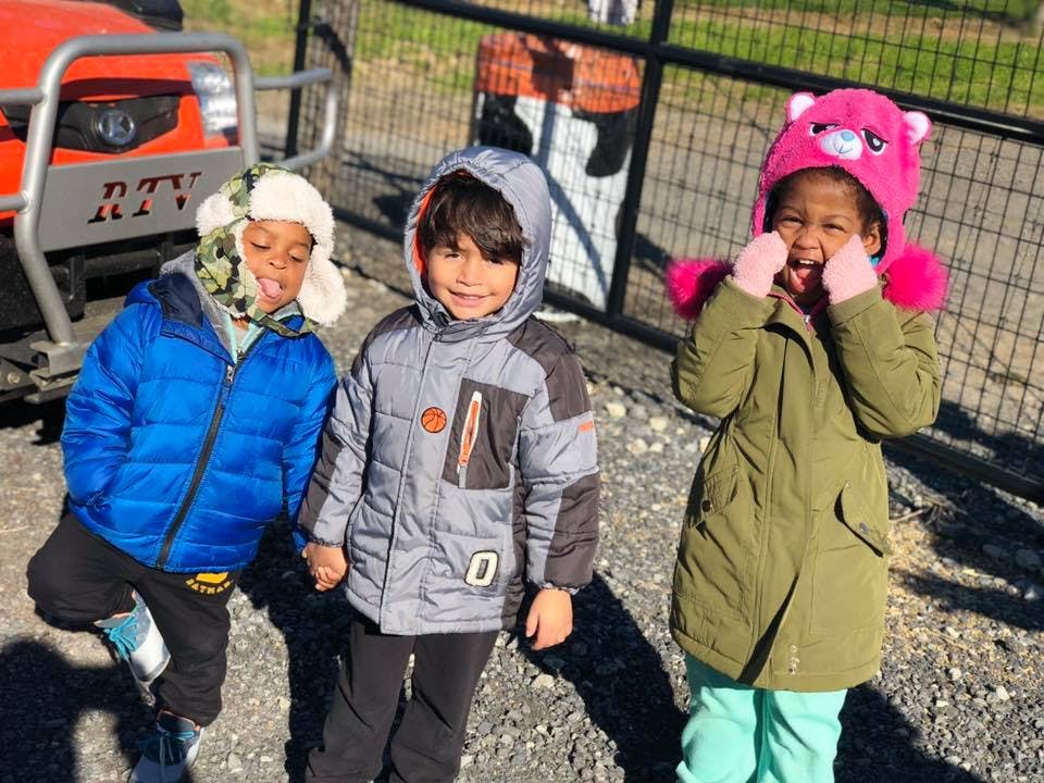 Three children in winter coats standing outdoors