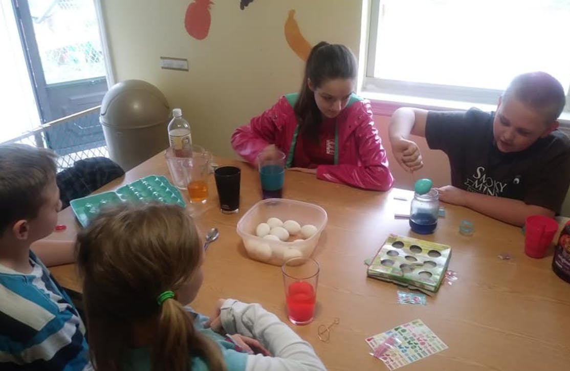 Children at a table decorating eggs