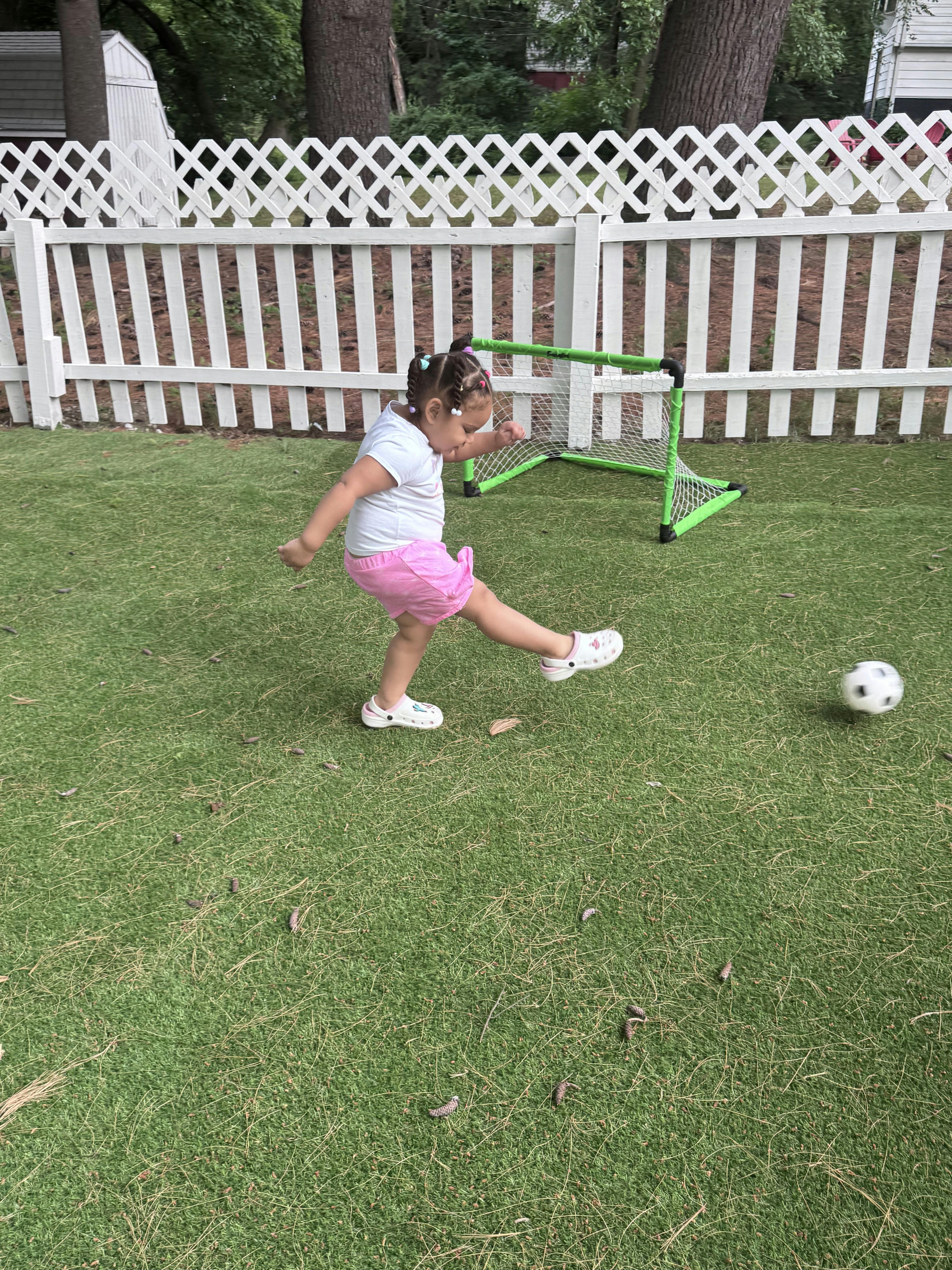Child kicking a soccer ball in a backyard