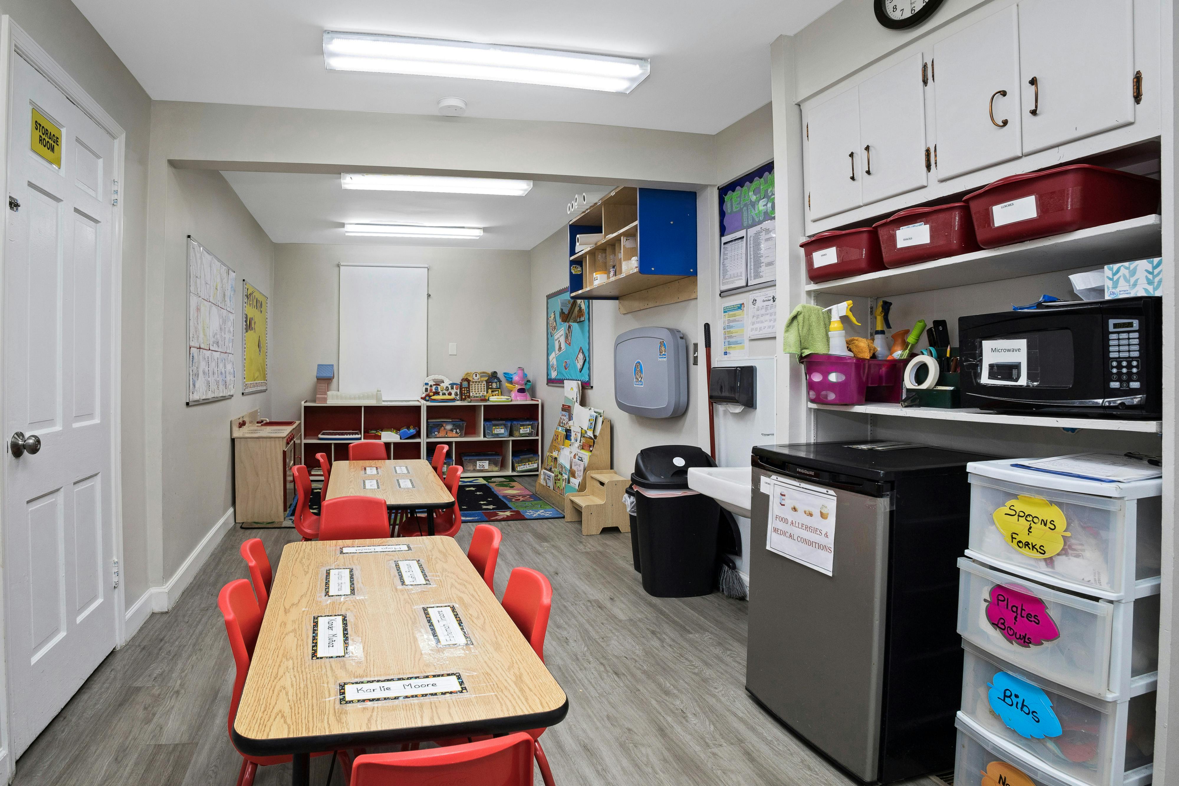 A colorful empty daycare classroom with small tables and chairs
