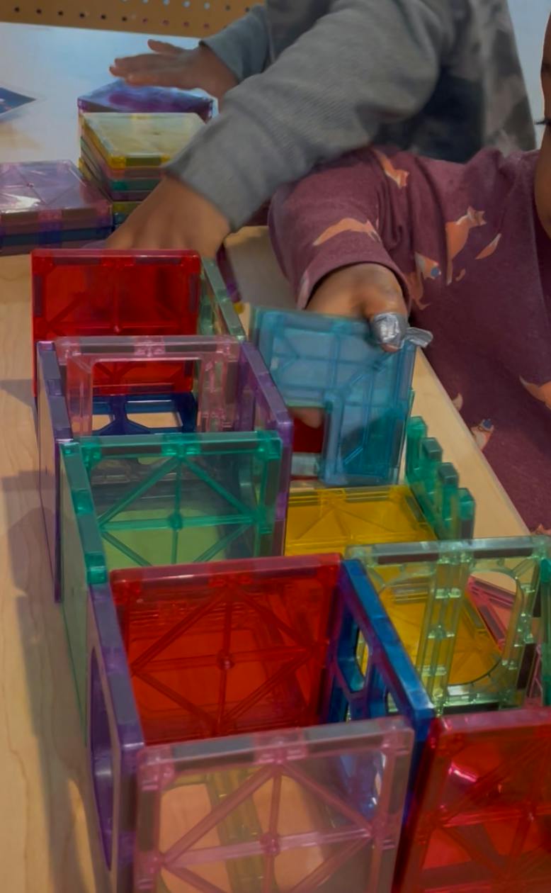 People building a structure with magnetic tiles
