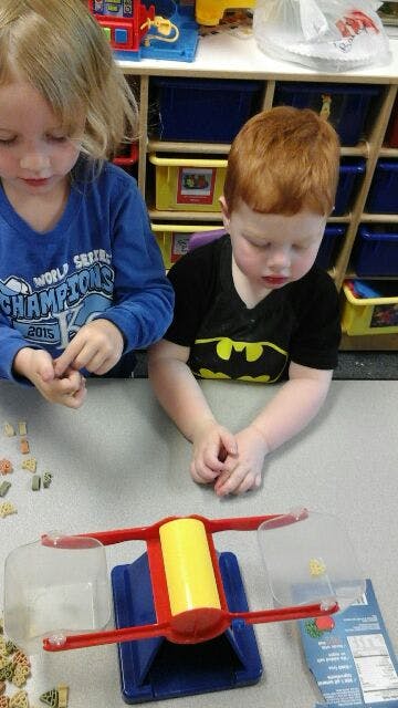 Two children playing with a balance scale and small objects