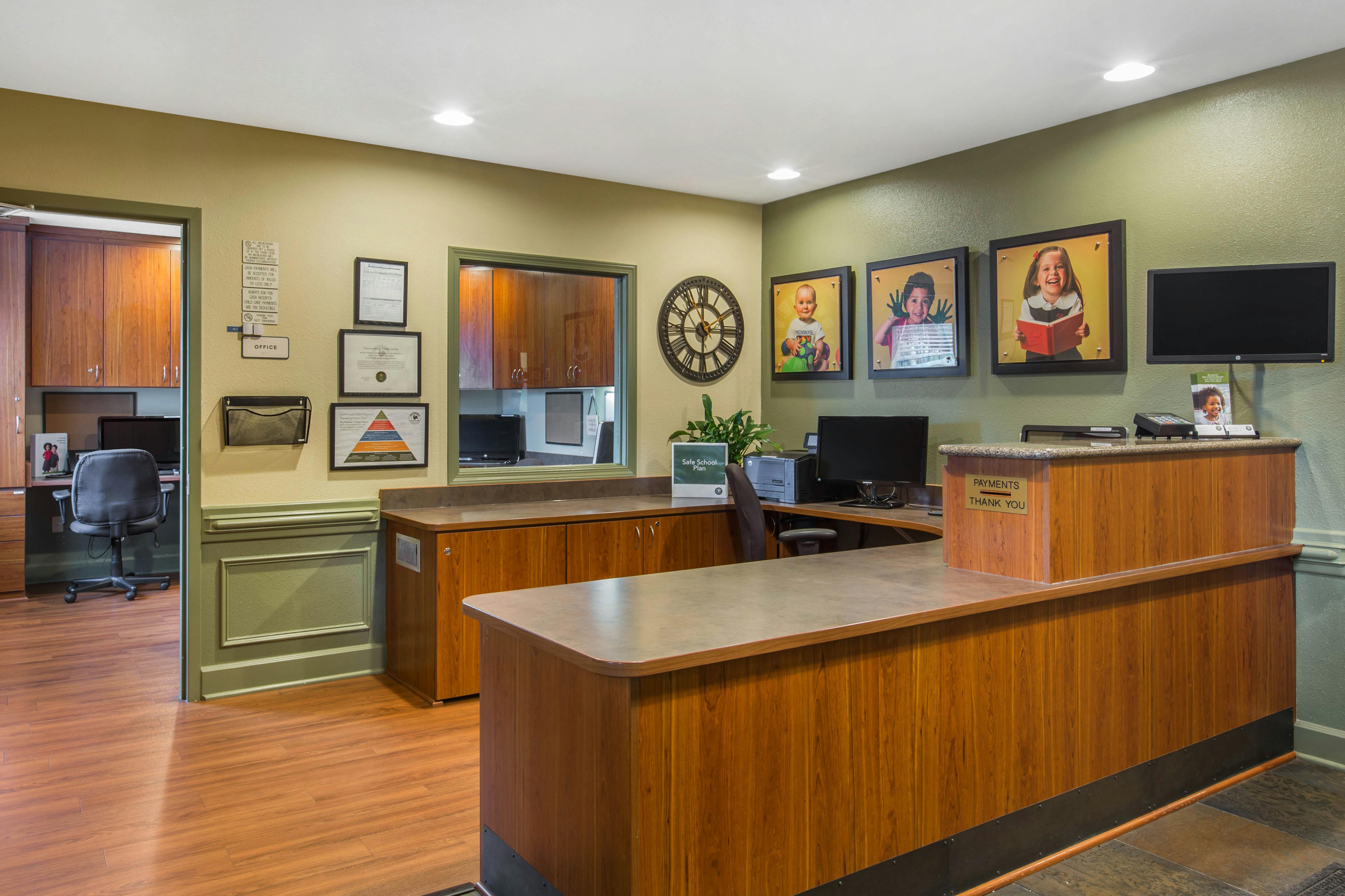 Reception desk with wood and dark green walls, office beyond