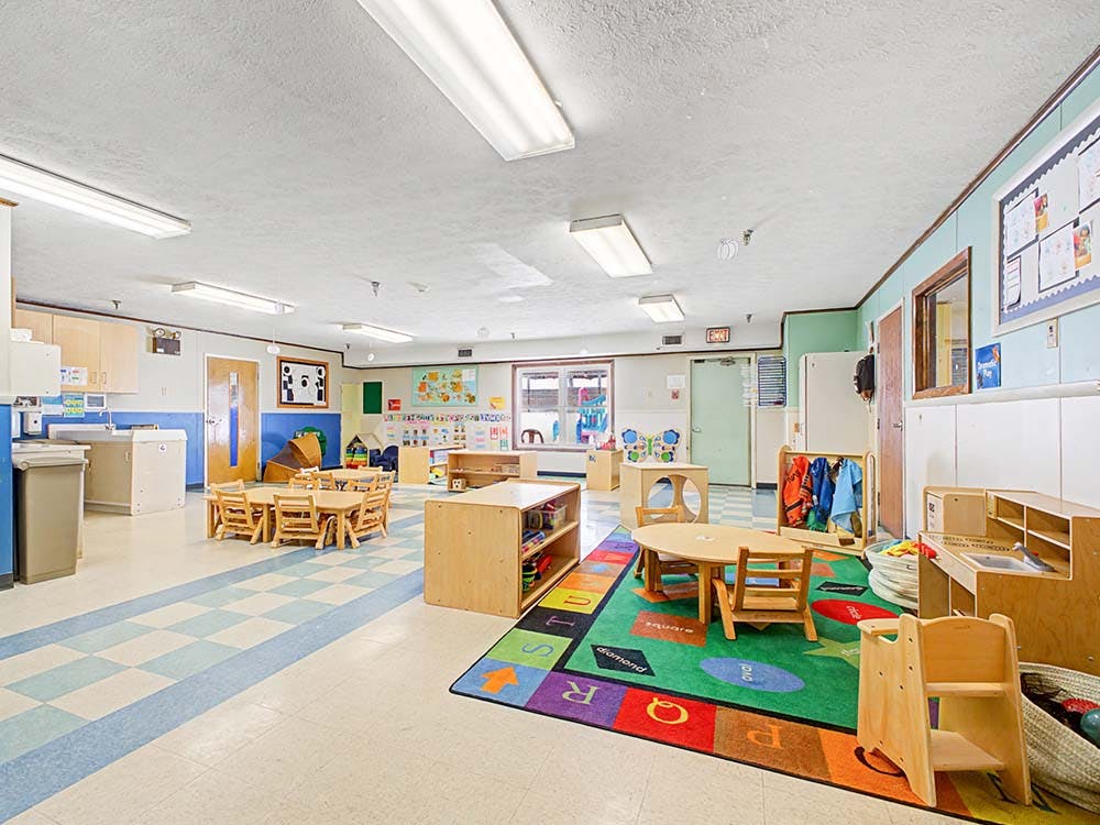 Empty colorful children's classroom with small wooden tables and chairs