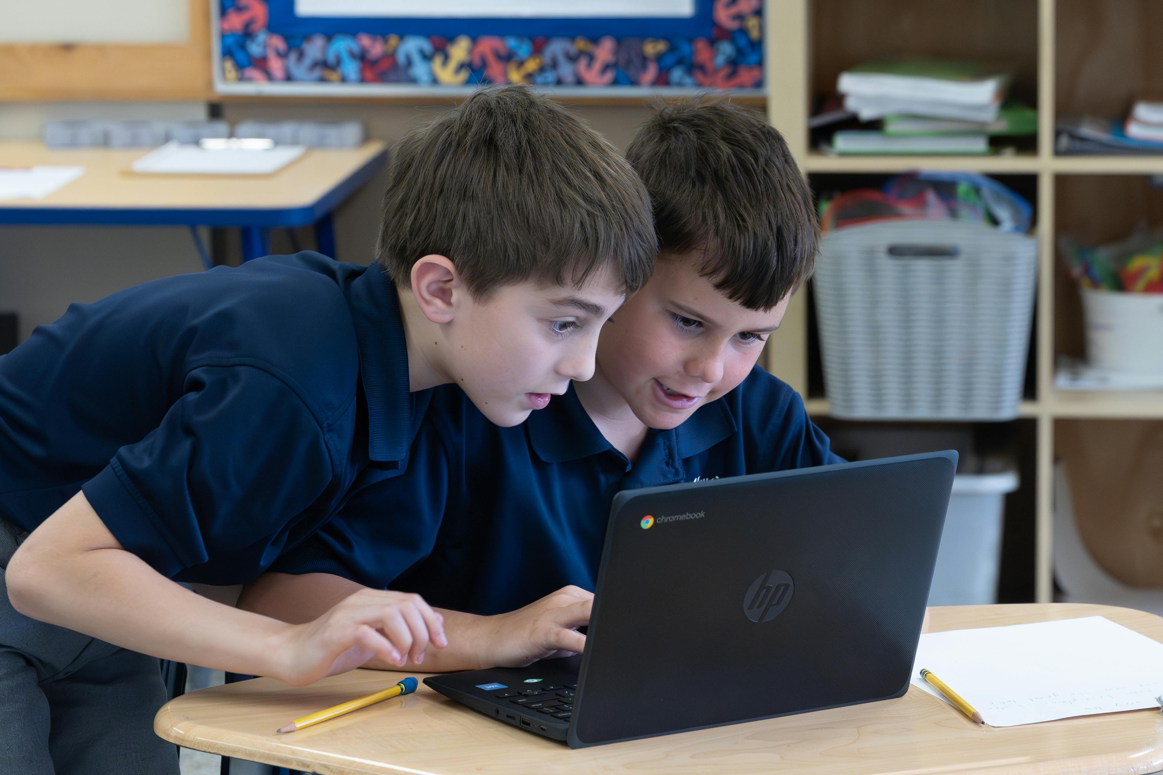 Two children looking at a laptop in a classroom