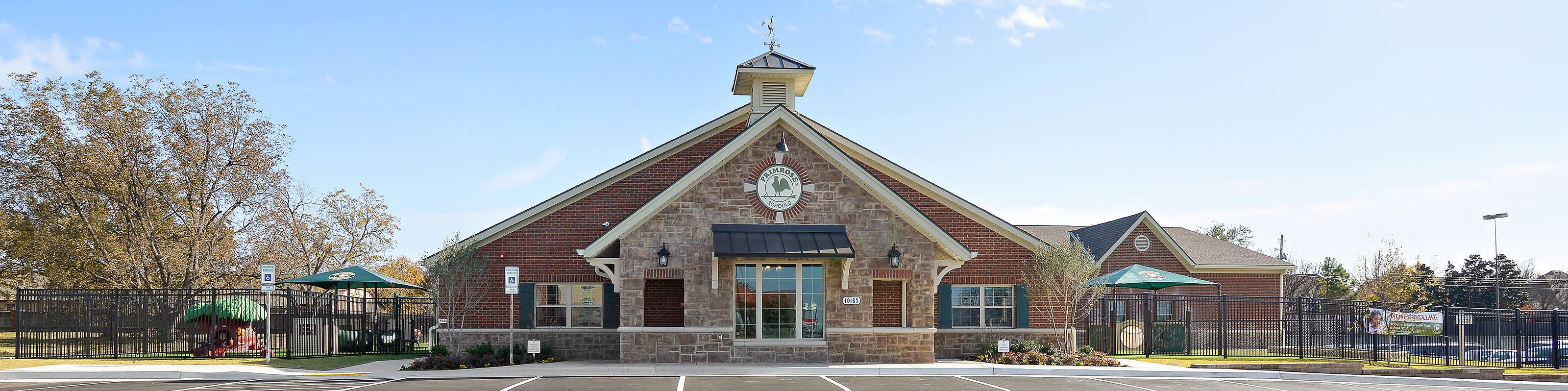 Brick building with a central steeple-like structure and a parking lot