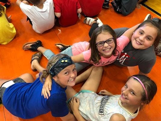 Four children lying on an orange floor, smiling