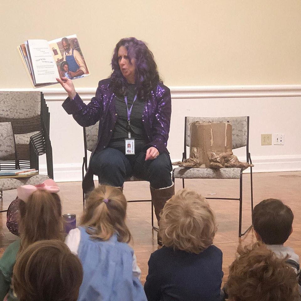 Person reading a book to children