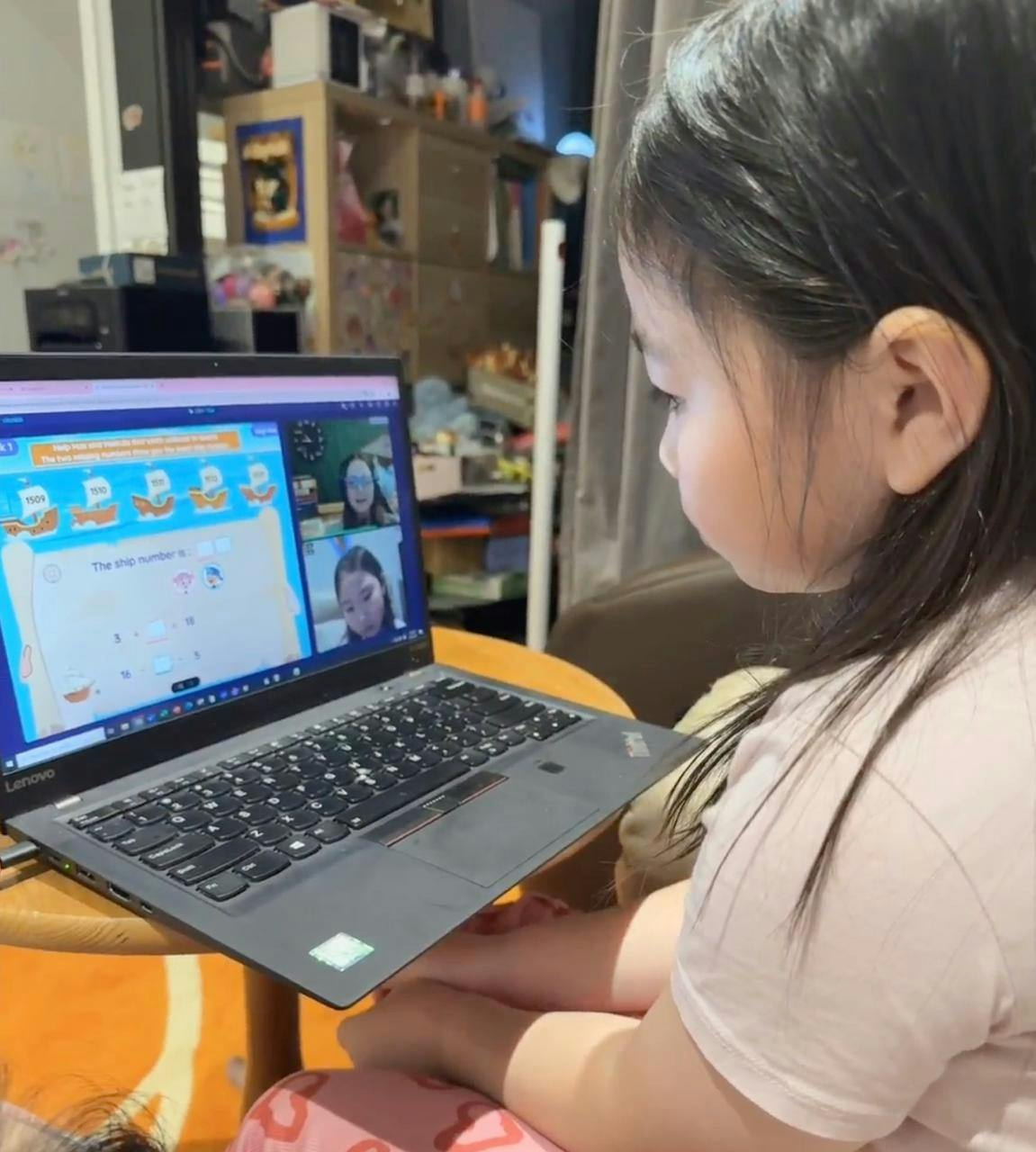 Child sitting at a desk participating in an online school lesson on a laptop