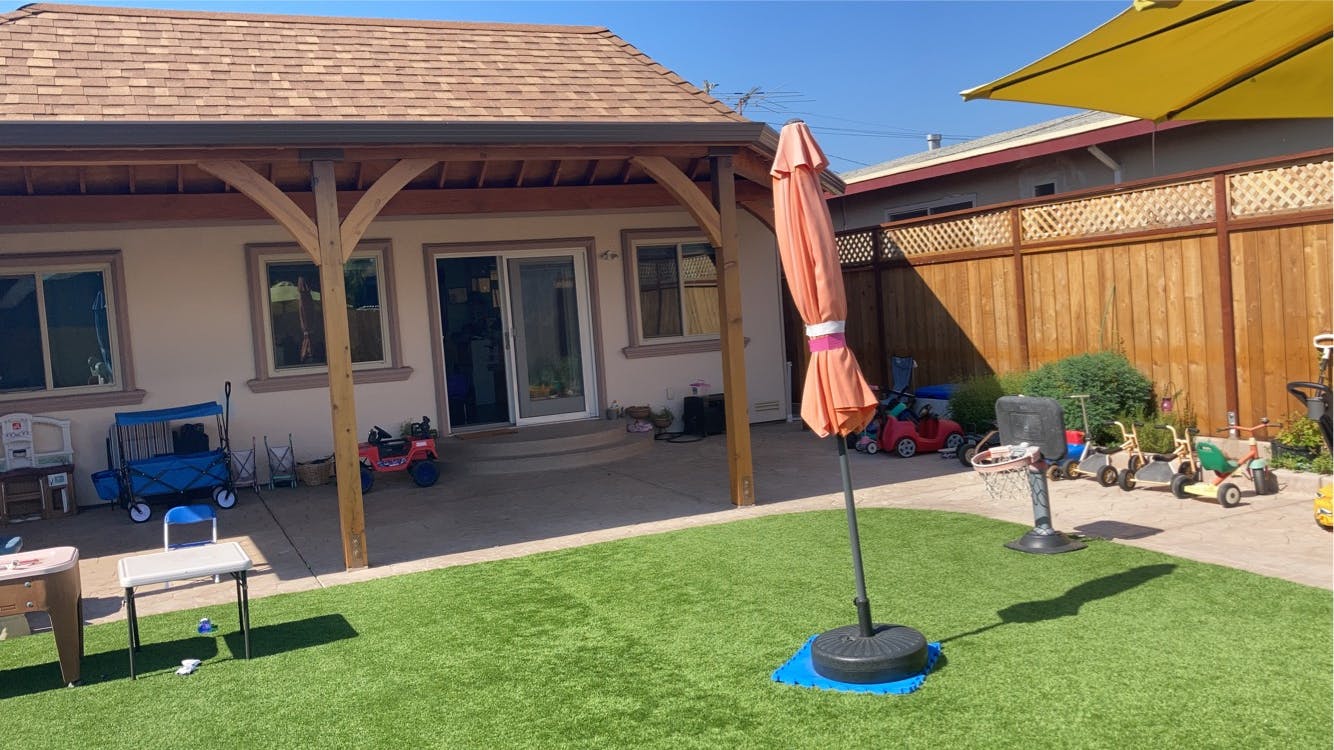 Backyard with artificial grass, patio, and closed umbrella