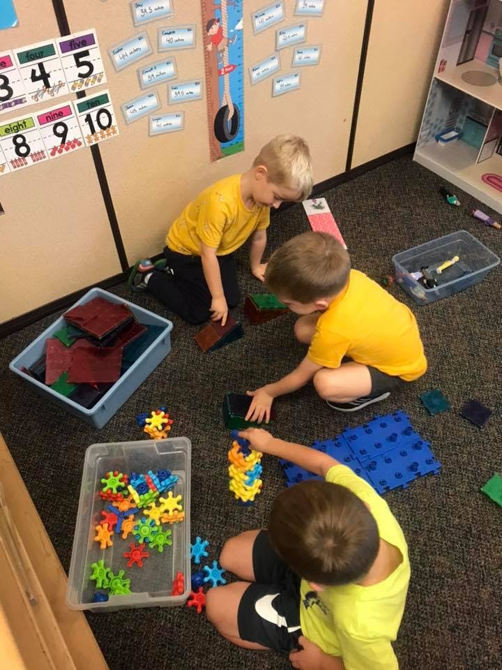 Three children playing with building toys on the floor