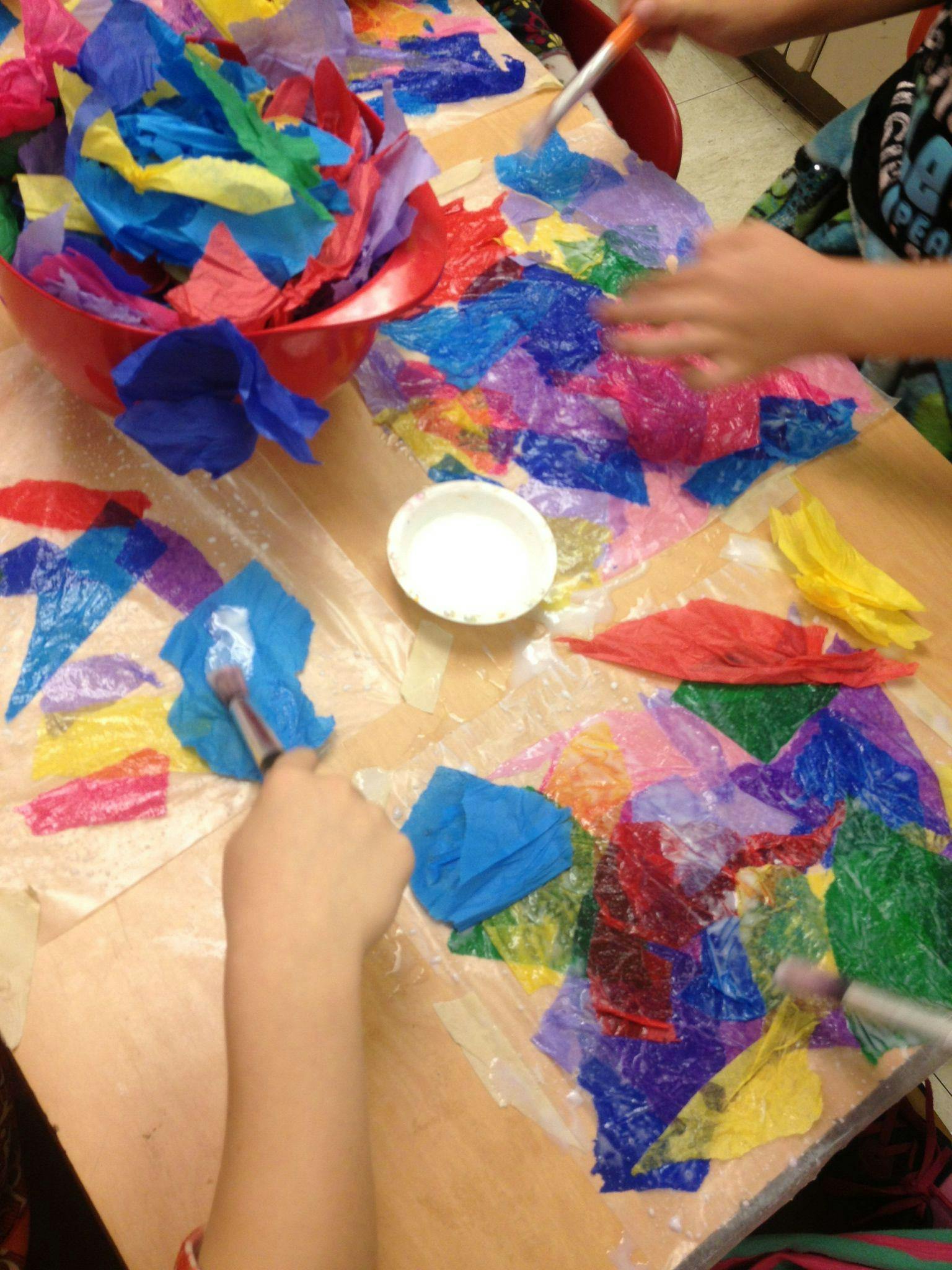People doing a craft with colorful tissue paper and glue