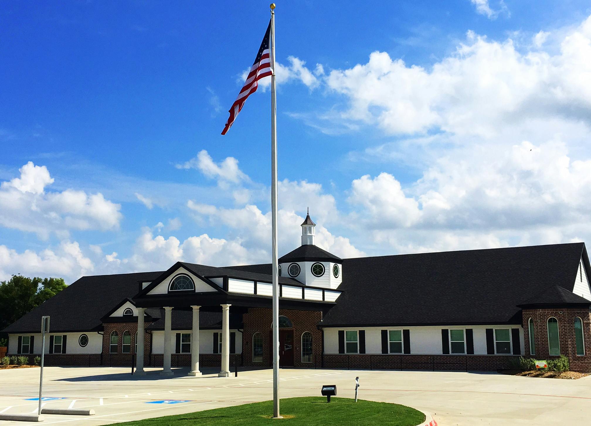 American flag on a flagpole in front of a building with a cupola