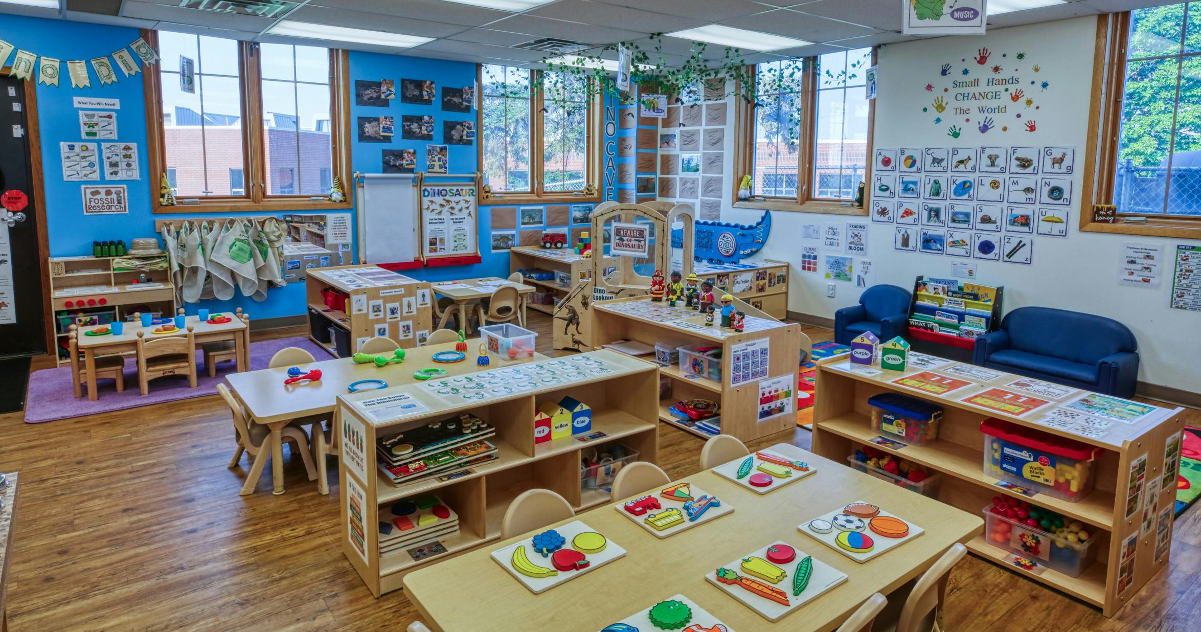 Colorful classroom with small tables, chairs, and shelves filled with educational toys