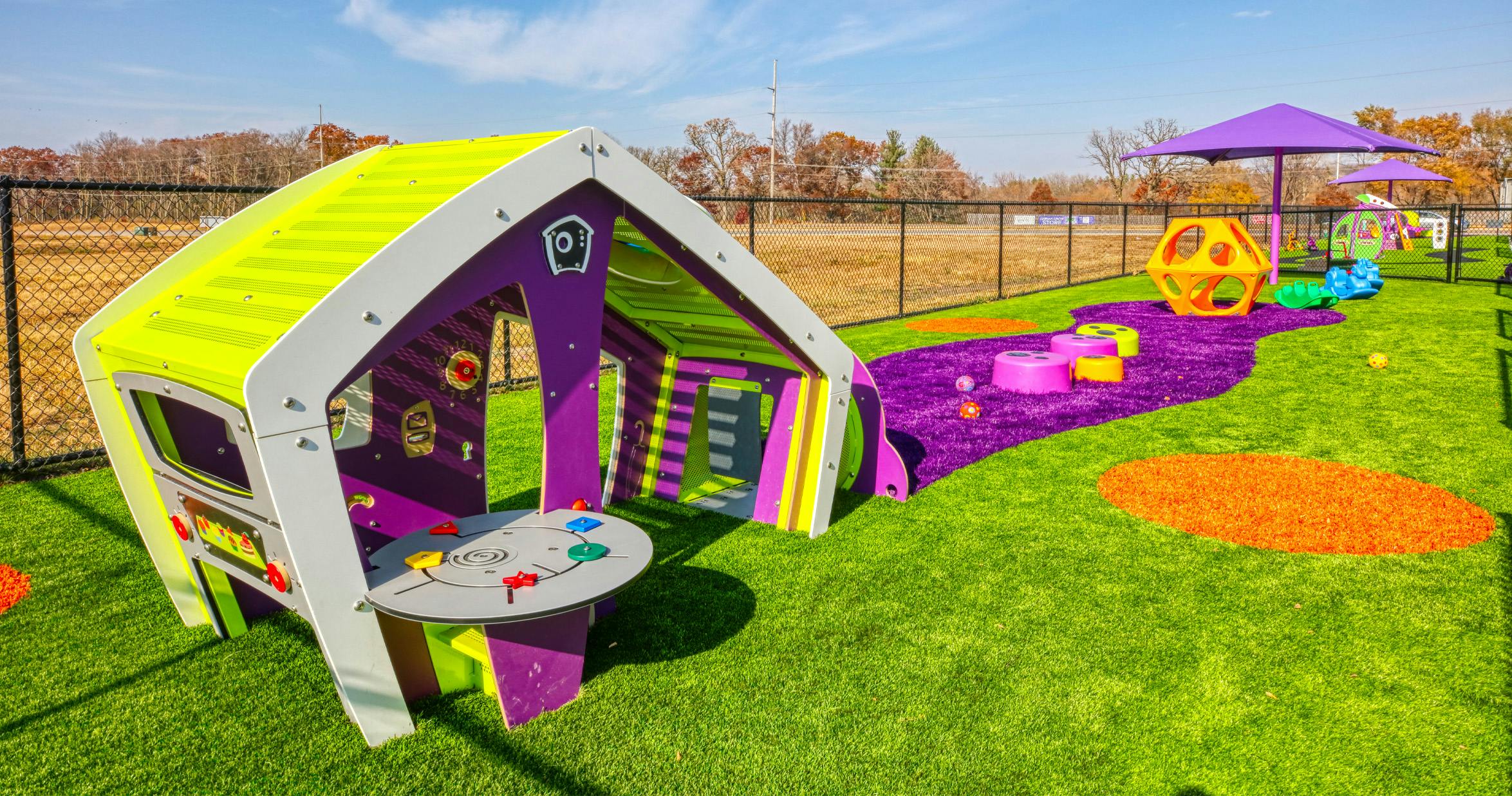 Colorful playground with house structure and soft play elements on artificial turf