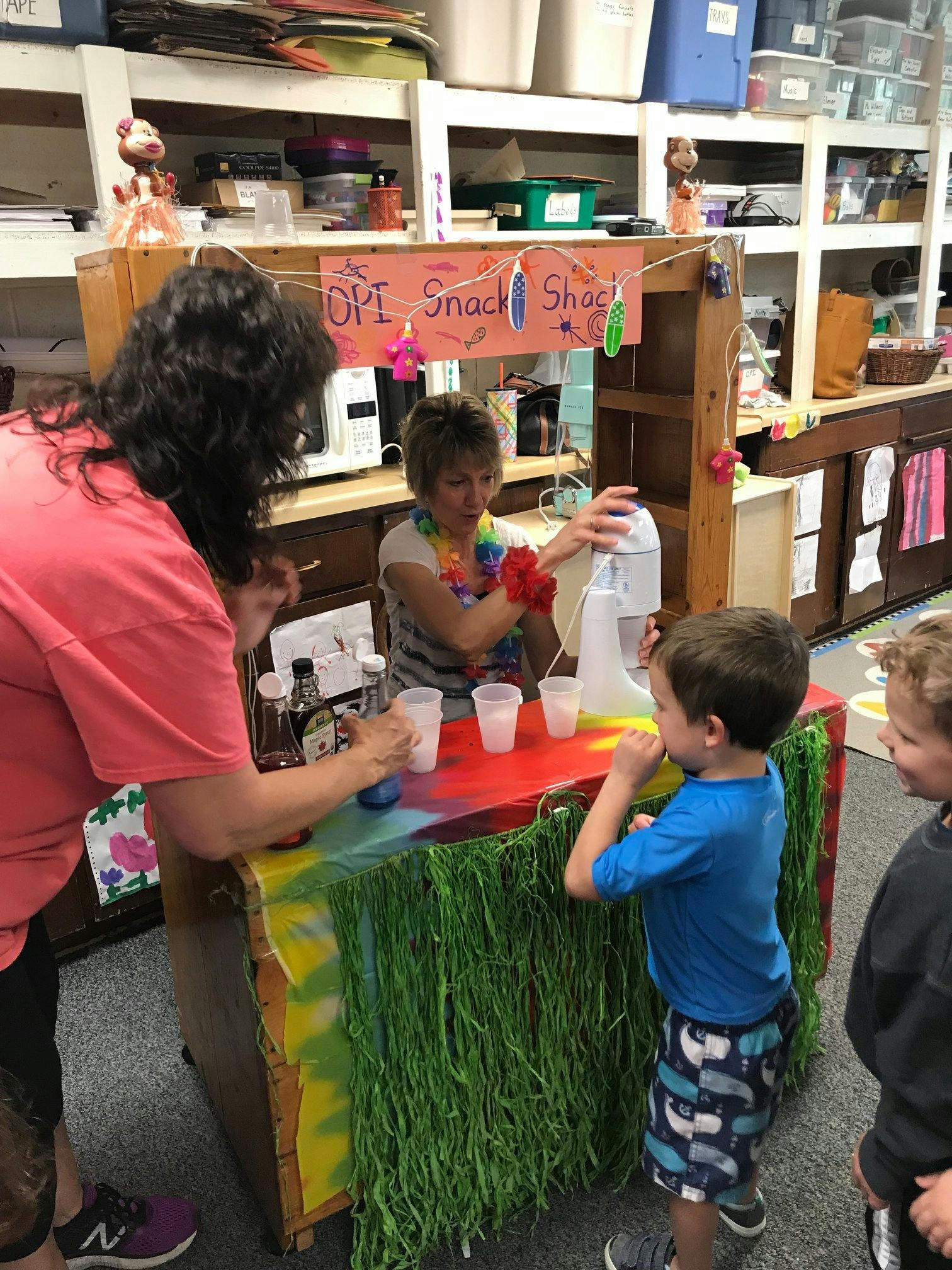 Two people and two children at a snack stand with a sign that reads "Snack Shack"