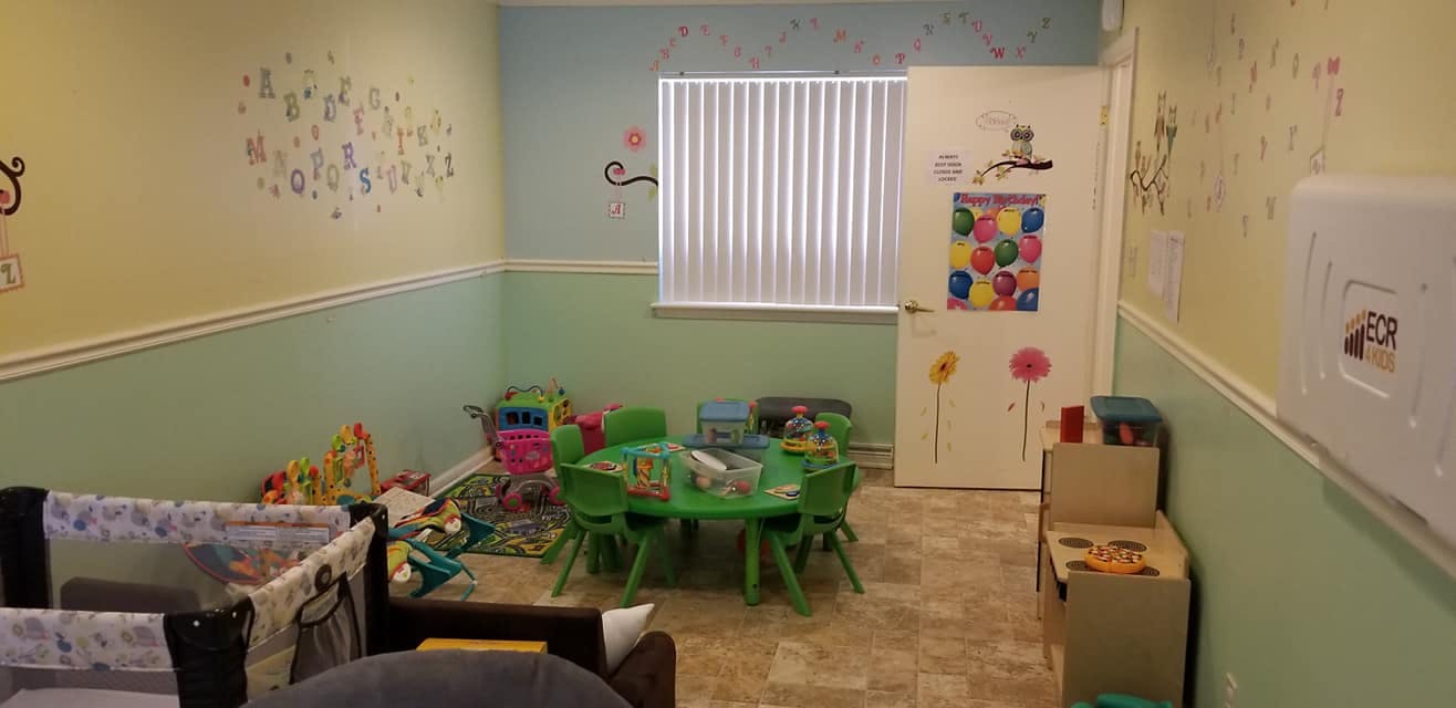 Playroom with a green table and chairs, crib, and toys