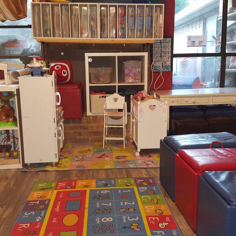 Playroom with colorful rugs, storage units, and child-sized furniture