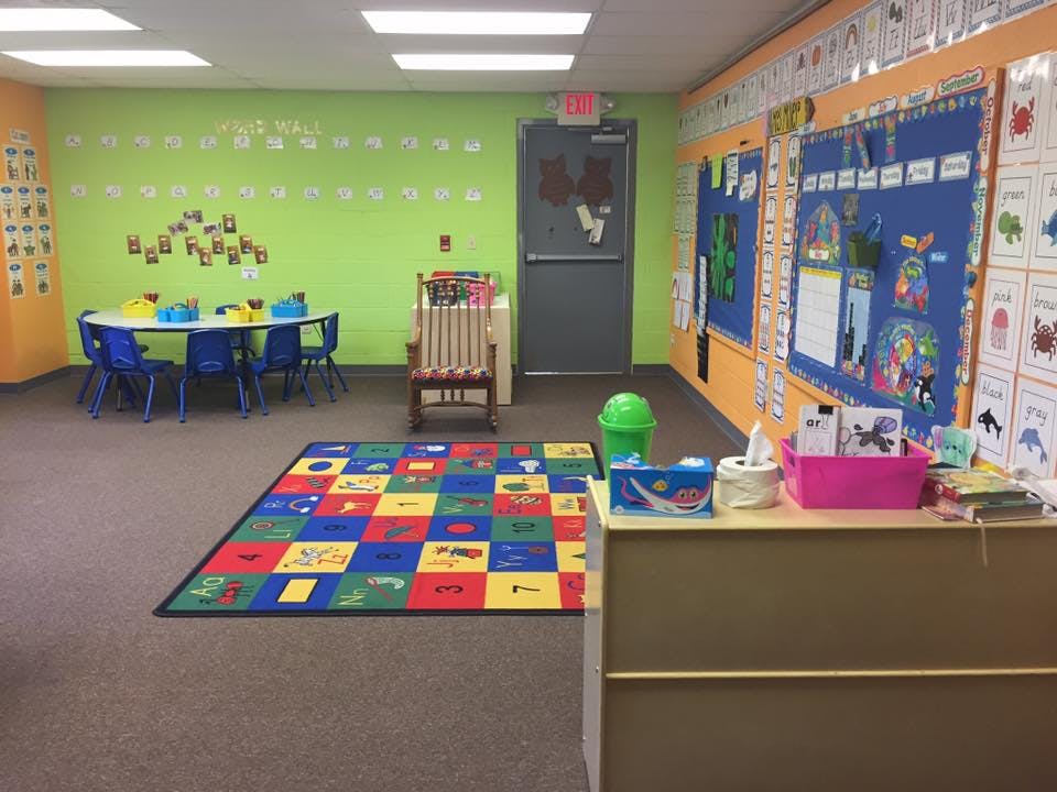 A colorful classroom with a small table and chairs, and a patterned rug