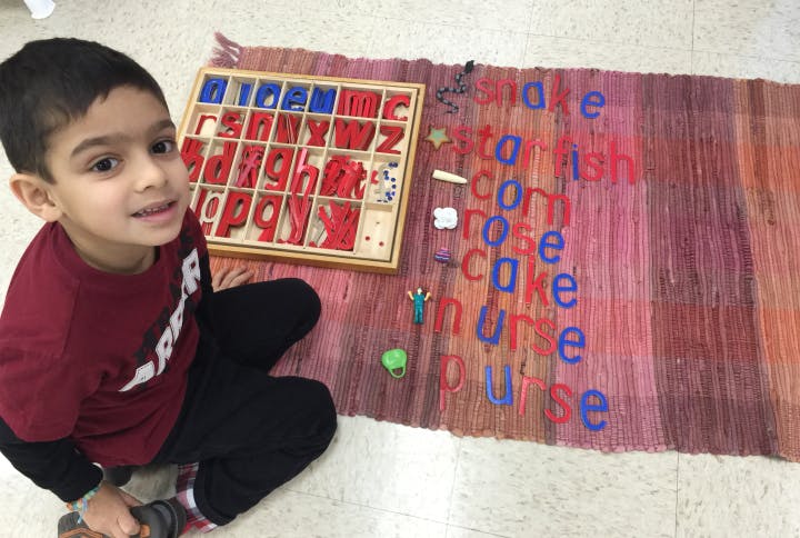 Child with alphabet tray and words spelled out on a mat