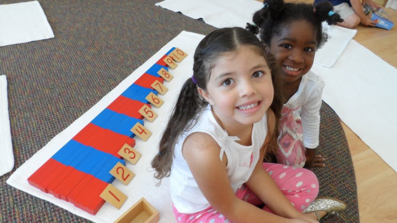 Two children sitting on the floor with a number rod math learning tool