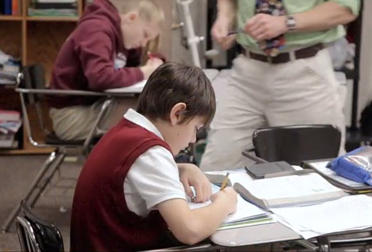 Child writing at a desk in a classroom