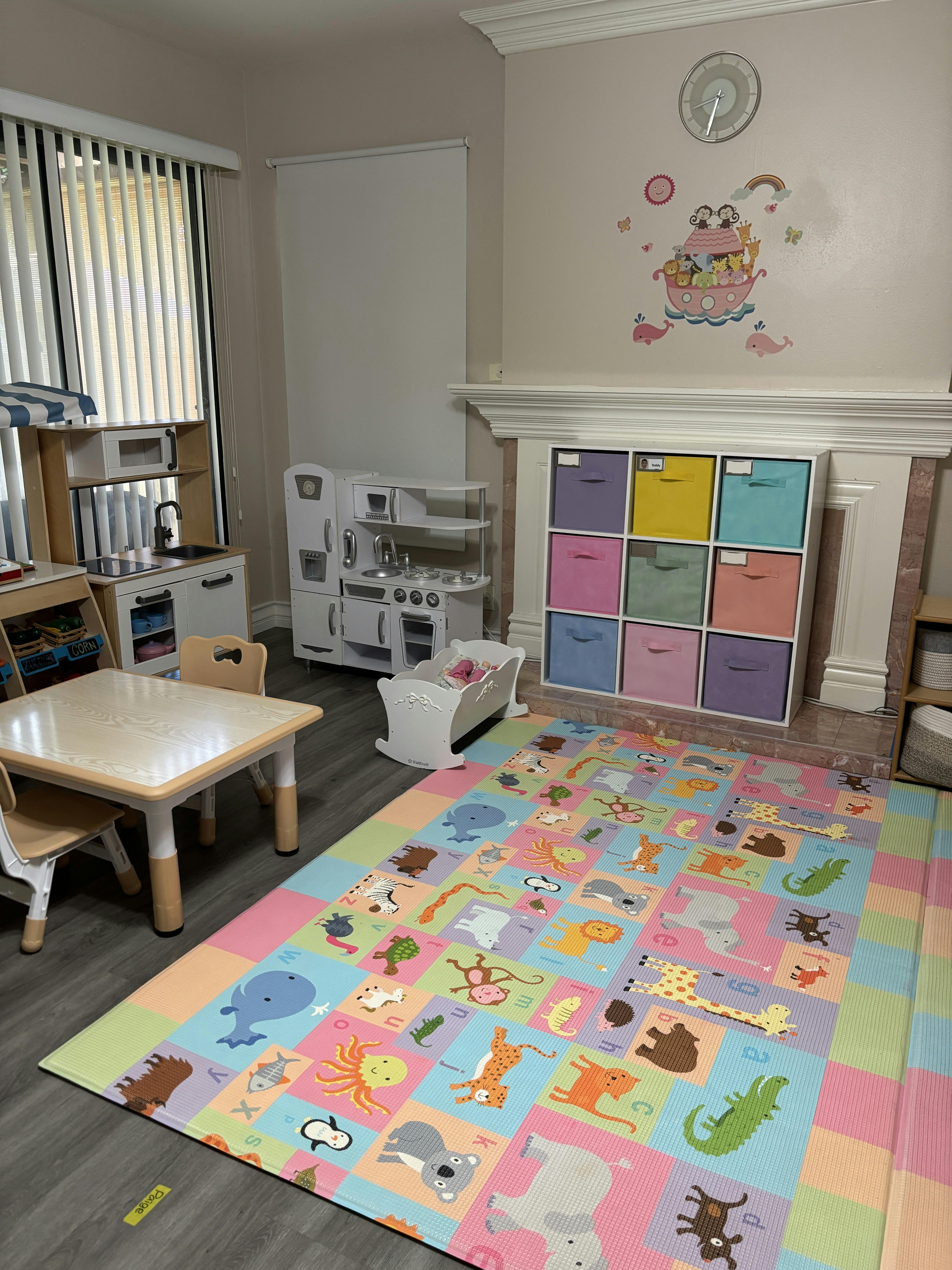 Playroom with a colorful animal alphabet mat, play kitchen, and small table