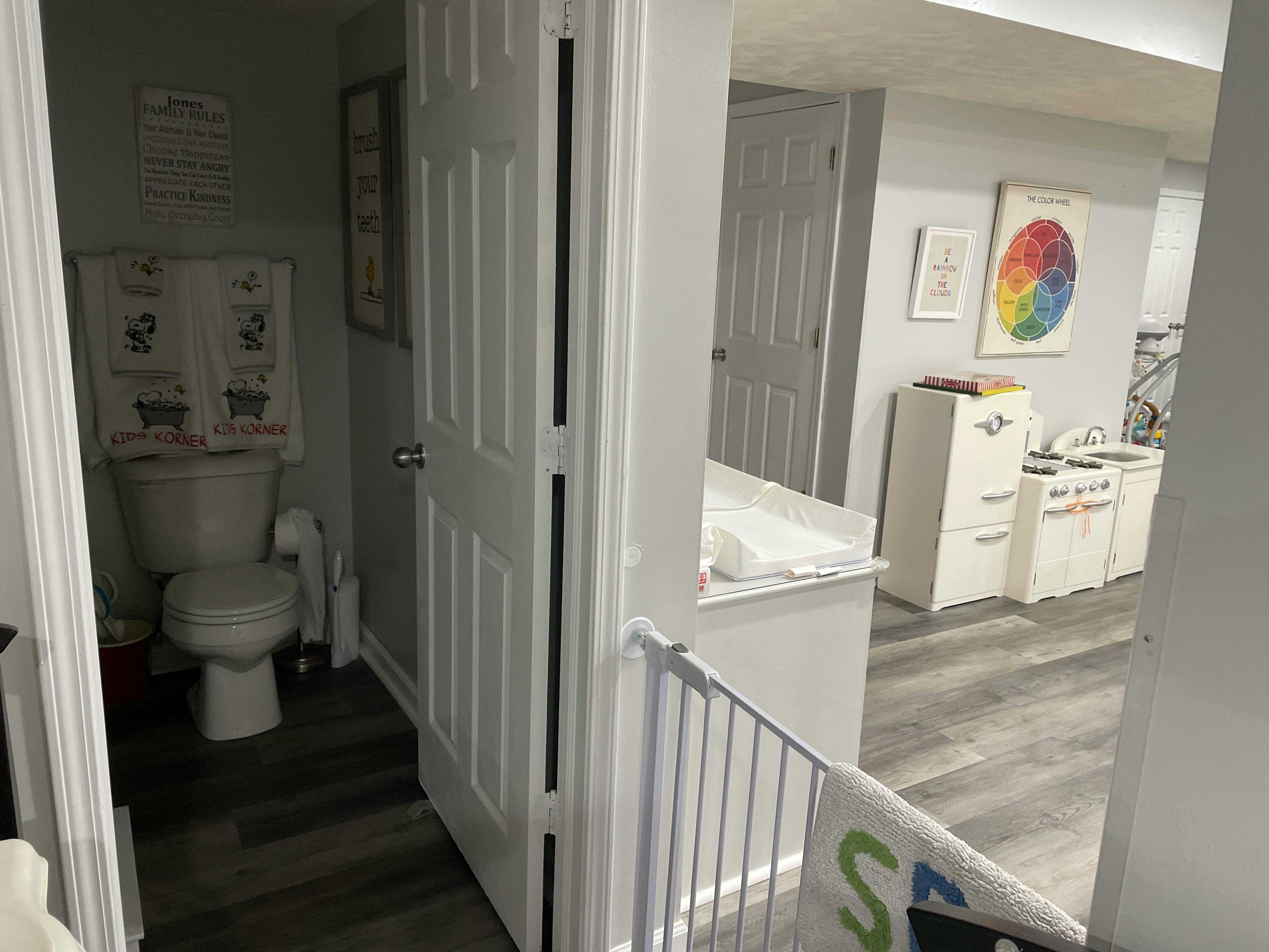Toilet in a bathroom with an open door leading to another room