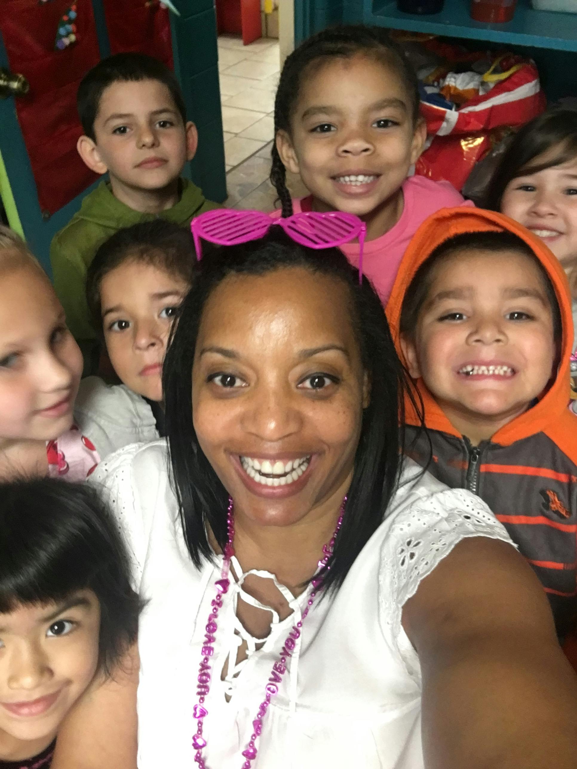Person smiling with several children around them