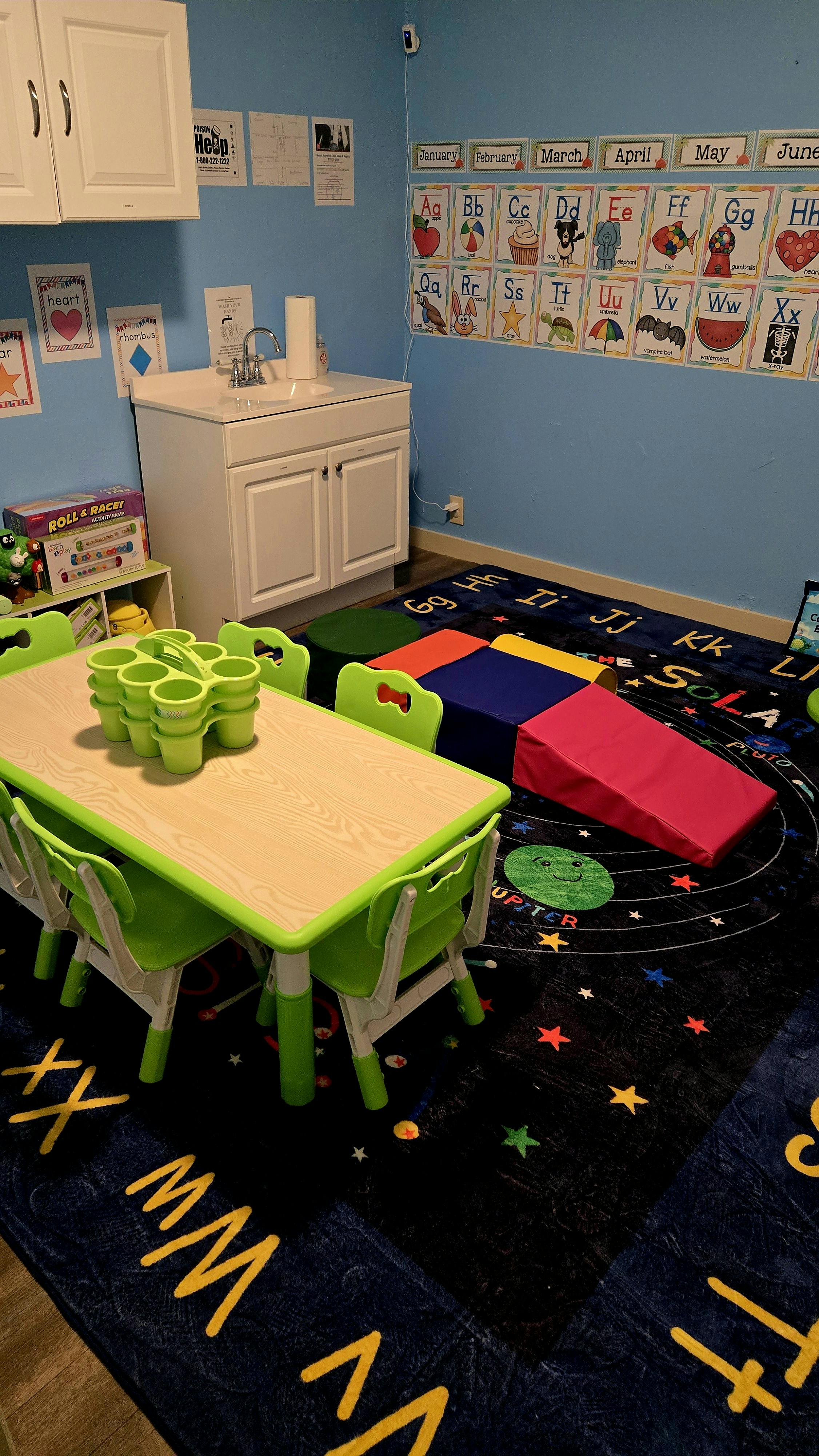 Classroom with small table and chairs, sink, and alphabet chart