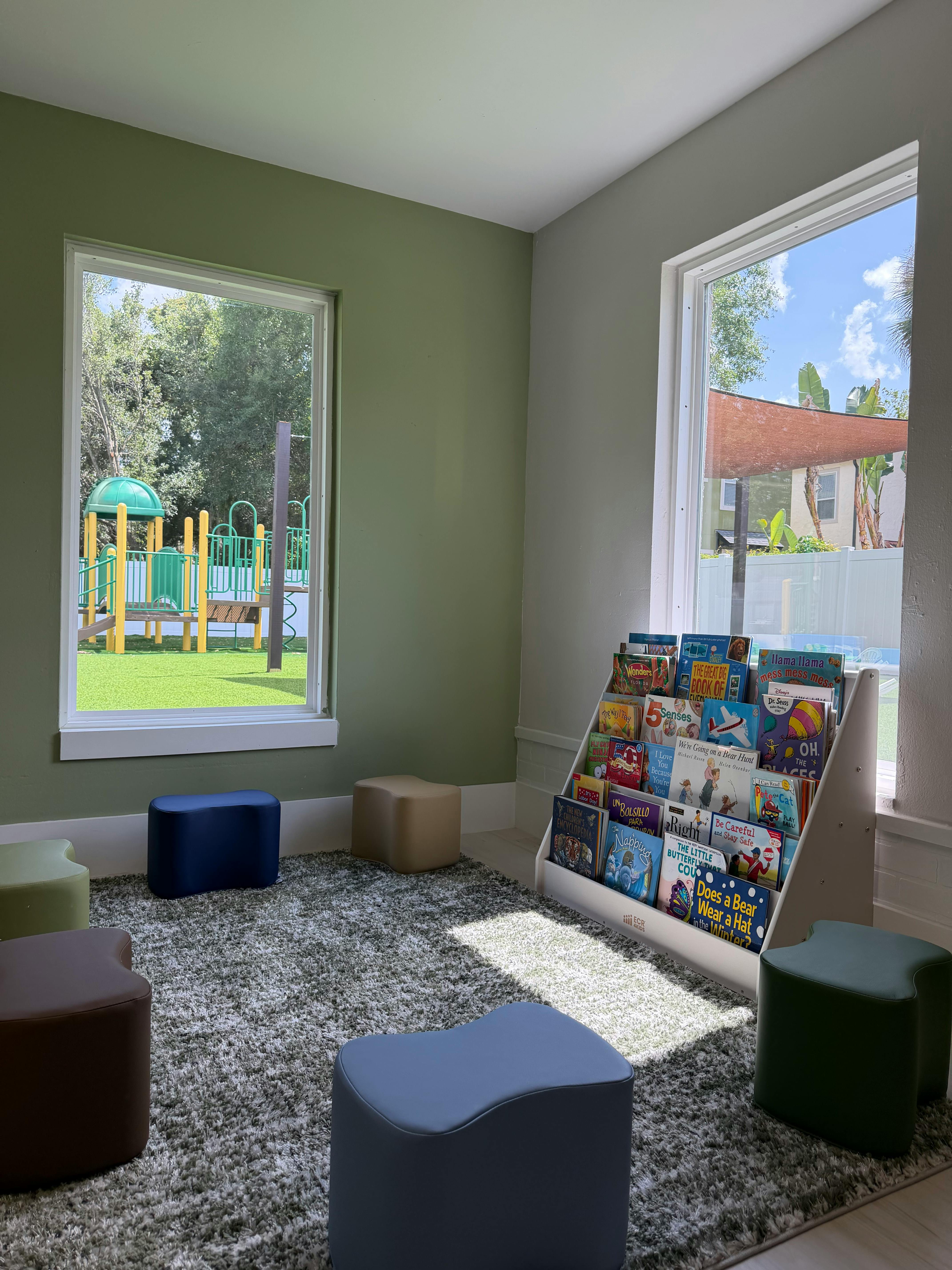 Childrens book display shelf with small stools on a carpeted floor