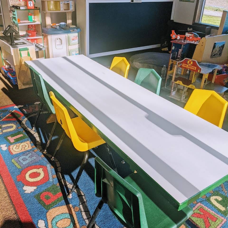 Long table with yellow and green chairs in a classroom
