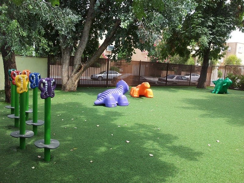 Playground with green artificial turf and colorful animal-shaped play structures