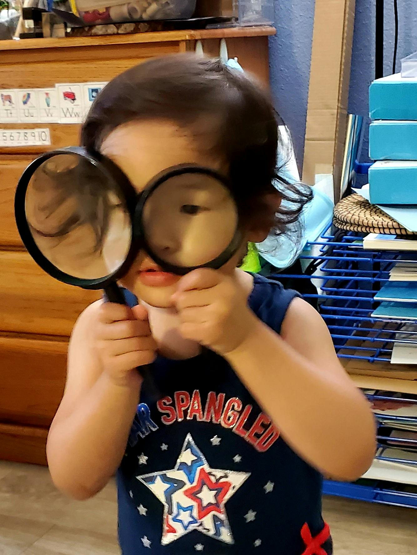 Child holding two magnifying glasses up to their face