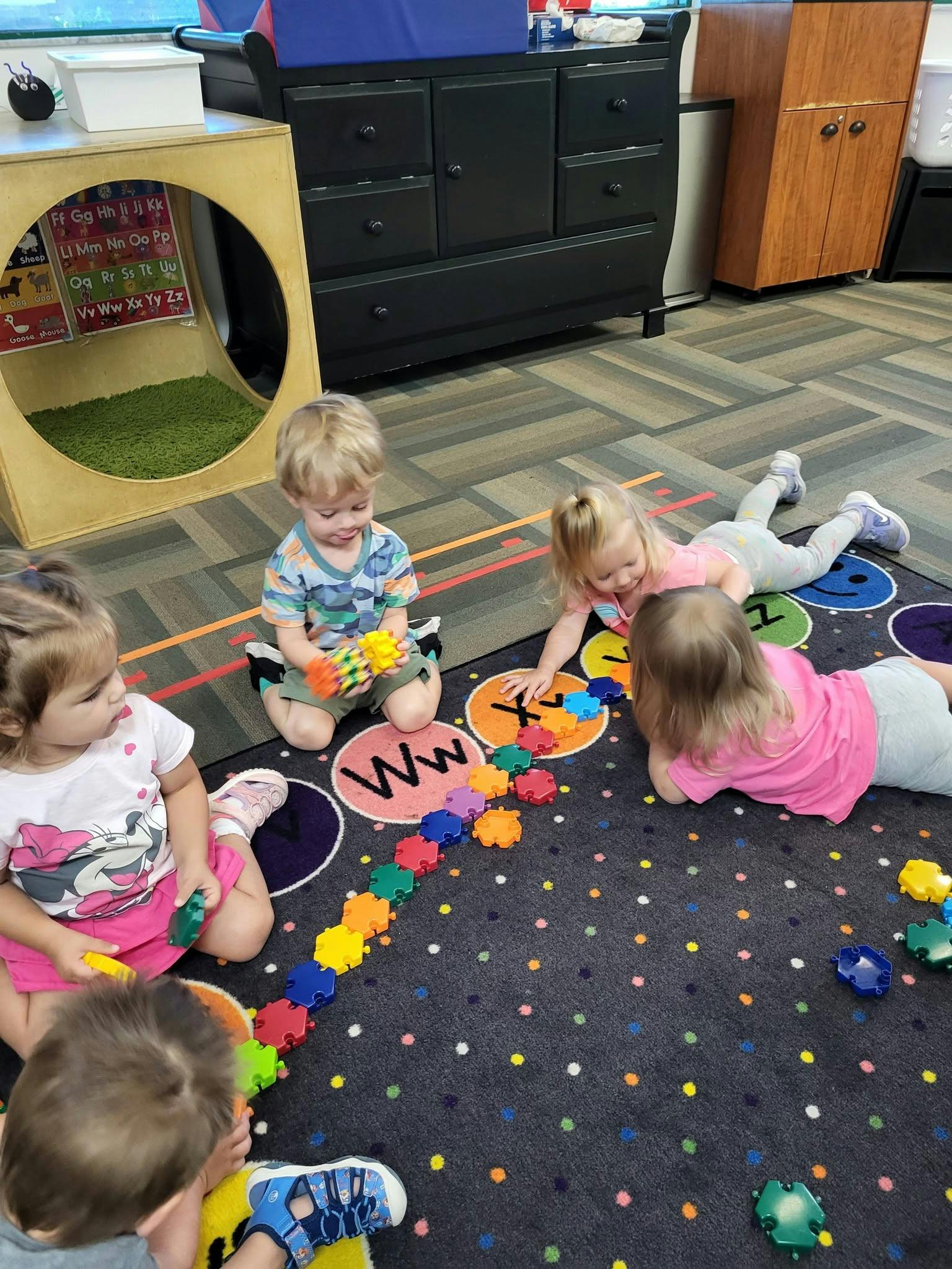 Children playing with colorful plastic building blocks on a classroom rug
