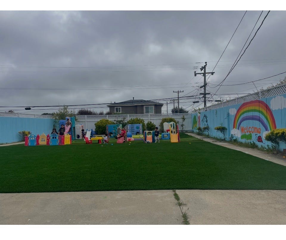 Children playing on colorful playground equipment in a fenced yard